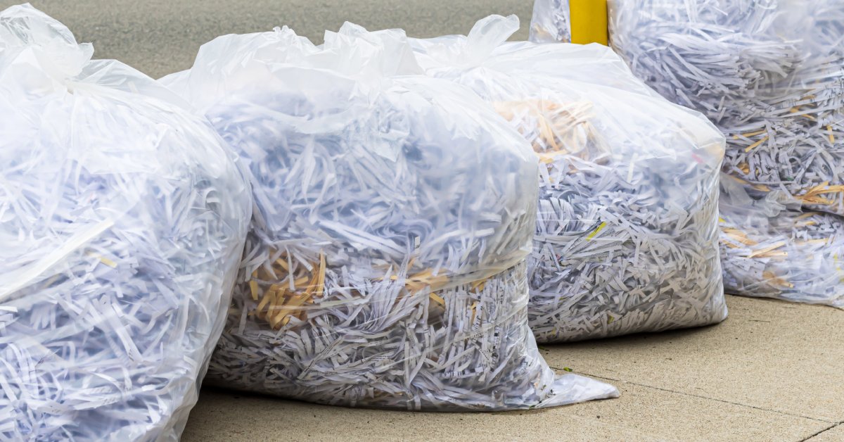 Clear trash bags filled with the shredded remains of documents sitting on a curb waiting to be picked up.