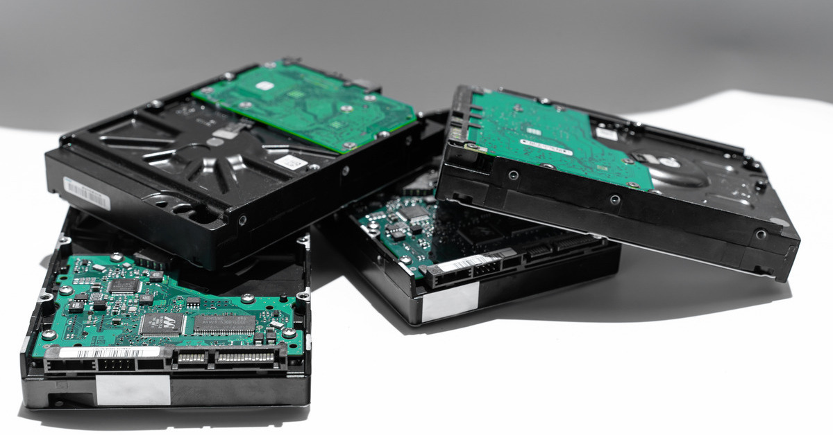 A group of hard drives with green motherboards stacked on top of one another in a small cluster over a white background.