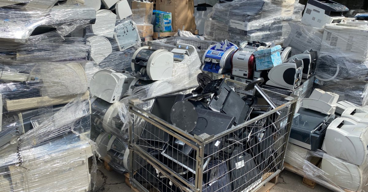 Several piles of old electronics equipment bundled together on pallets in an outdoor sorting area.