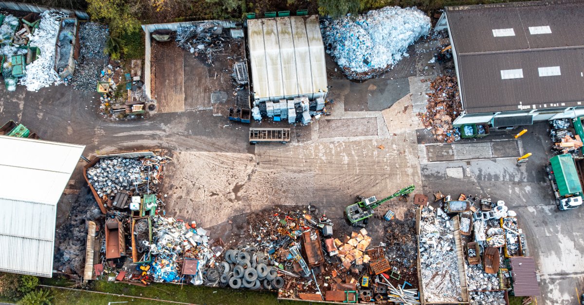 An overhead view of an outdoor recycling plant with piles of different types of waste, including tires and metal parts.