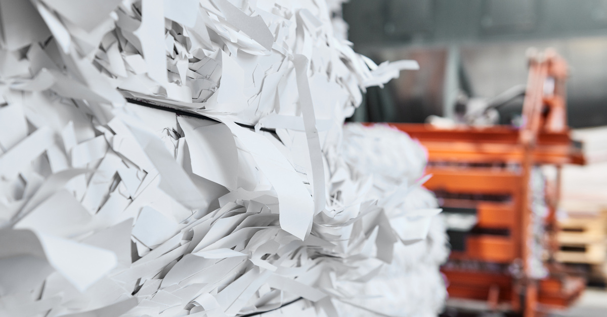 A pile of paper bound together with a strap siting in a warehouse facility ready to be shredded or recycled.