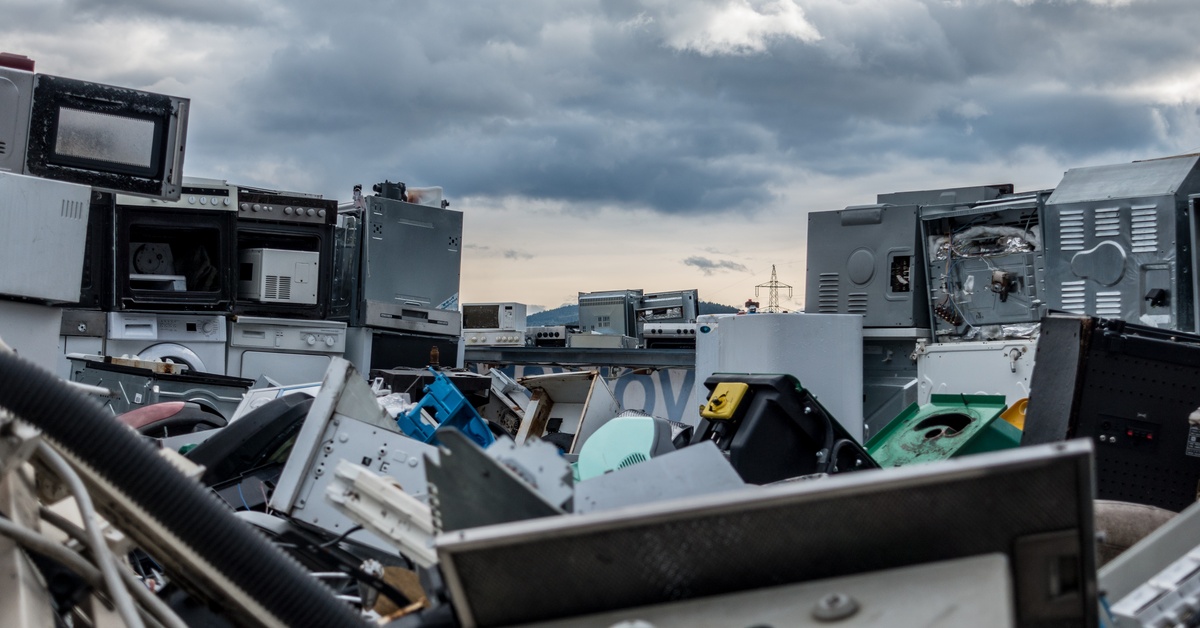A view of a sky with clouds obscuring the sun from on top of a pile of electronic waste in need of recycling.