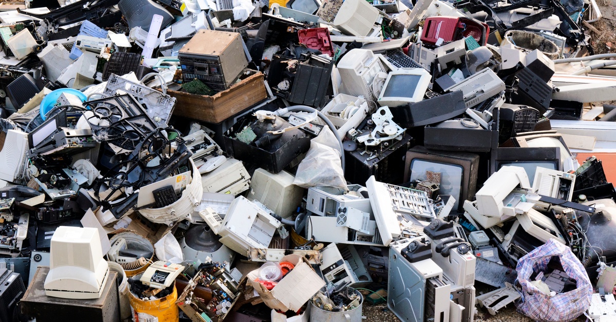 A large pile of electronic waste, including CRT TVs, computer monitors, and hard drives. The pile nearly fills the frame.