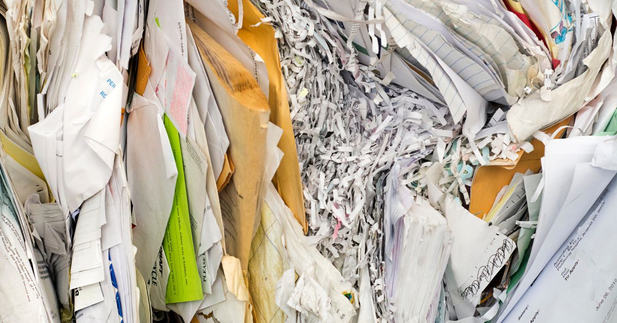 Stacks of old documents squished together in a pile with bits of shredded paper in the middle of it all.