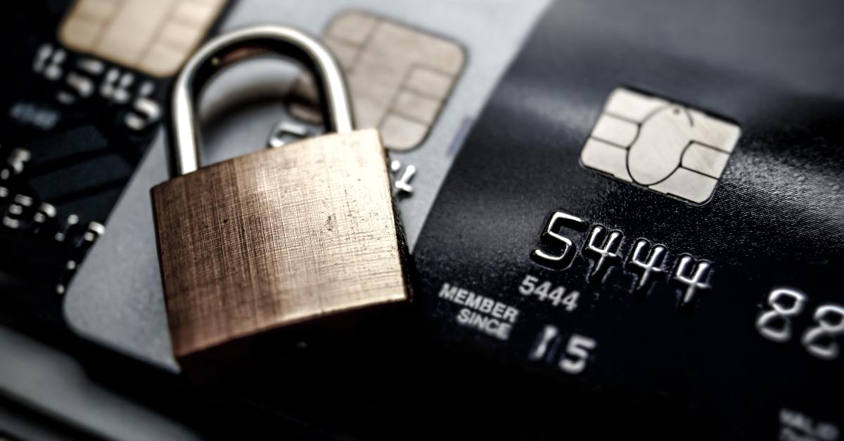 A small lock with brushed metal sitting on top of a row of credit cards with visible RFID chips.