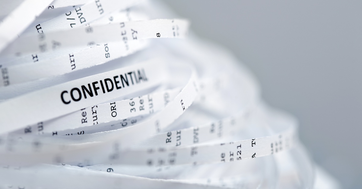 A collection of bend shreds of white paper documents, with the word "CONFIDENTIAL" visible on one of the thin shreds.