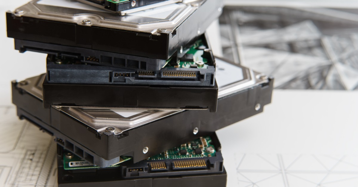 A stack of misaligned physical hard drives, all in different styles, sitting on top of a printed diagram.