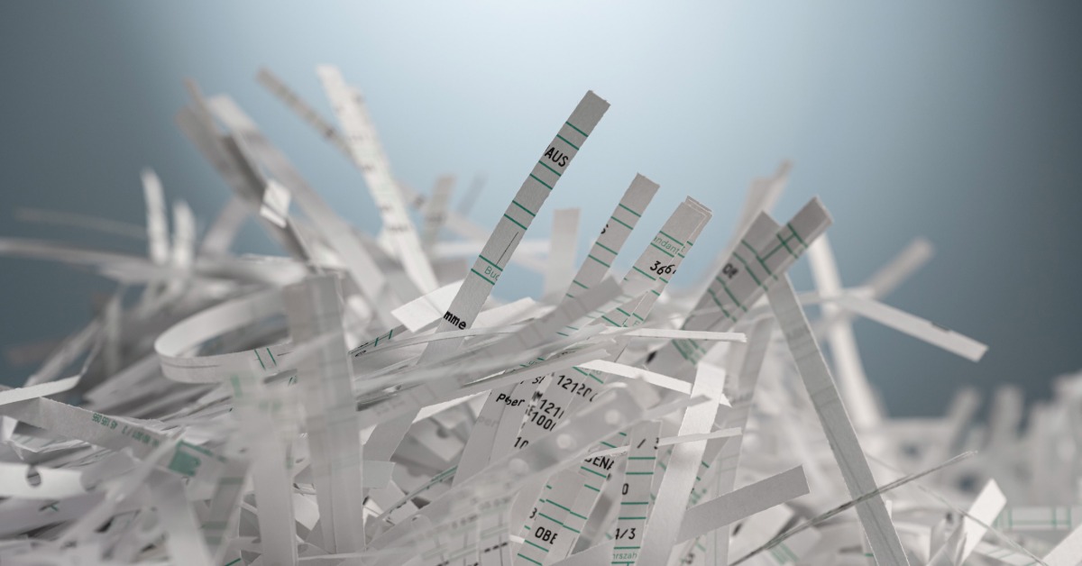 A close-up on a pile of shredded papers. The papers are now cut into thin slivers with jumbled text.