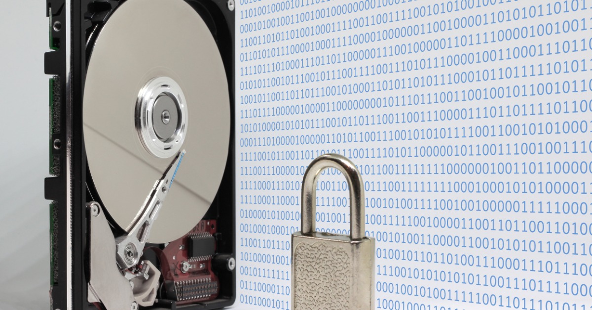 An exposed hard disk drive stands beside a small silver padlock. Rows of blue binary numbers fill the background.